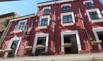 Detalle de la fachada roja con ventanas blancas y macetas en los balcones