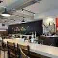 Interior del bar de Cork & Stem con mostrador blanco y luces colgantes