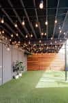 Área al aire libre con césped artificial y luces colgantes