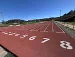 Pista de atletismo exterior con carriles numerados bajo cielo despejado