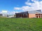 Vista exterior del Nuevo Polideportivo de La Pola en Siero con fachada moderna y césped frente a él