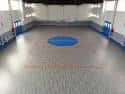 Interior de la sala polivalente con suelo deportivo y zona central azul
