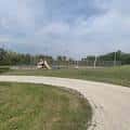 Sendero curvo que atraviesa el parque con zona deportiva al fondo