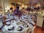 Sala de eventos decorada con mesas redondas y centros de flores púrpuras