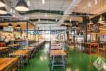 Área de comedor con mesas largas y ambiente industrial