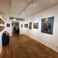 Vista del salón principal de la galería con cuadros colgados y mobiliario minimalista