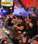 Vista del mostrador principal 'The Main' con clientes disfrutando bebidas