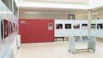 Salón principal del Espai Josep Vernis con paredes rojas y blancas, exhibiciones fotográficas y mobiliario para eventos