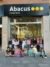 Grupo de niños y adultos posando frente a la entrada principal de la tienda Abacus