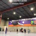 Interior del Dive Volleyball and Sports Center en Denver con jugadores en cancha y banner de bienvenida