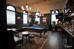 Interior del pub con mesa de billar, iluminación cálida y ambiente acogedor para eventos sociales