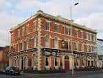 Vista exterior del Derby Brewery Arms en Manchester, mostrando su fachada de ladrillo rojo y arquitectura clásica