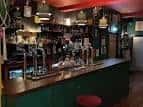 Barra principal del pub con grifos de cerveza y estantería de botellas