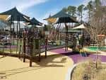 Área de juegos infantil con estructuras coloridas y sombra en Laurel Hills Park