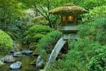 Lámpara de piedra tradicional junto a un arroyo en el jardín japonés