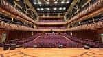 Interior del auditorio principal con butacas rojas y escenario amplio