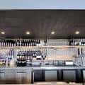 Interior del bar de Négociant Winery con estanterías de botellas y grifos de vino