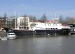El barco Thekla visto desde el agua con edificios urbanos al fondo