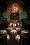 Salón de eventos preparado para cena con mesas redondas y arco decorativo iluminado