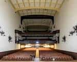 Vista interior del auditorio con butacas rojas y balcones clásicos