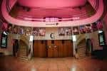 Hall principal del teatro con iluminación rosa y cartelera de eventos