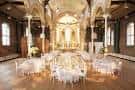 Interior del Hallé St Peter's decorado para una boda con mesas redondas y sillas blancas