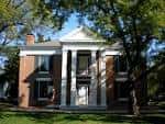 Vista frontal de la casa histórica con columnas neoclásicas y fachada de ladrillo