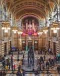 Gran vestíbulo interior con órgano monumental, techos abovedados y visitantes recorriendo el espacio