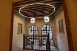Interior del palacio con escalera de madera y ventanales arqueados