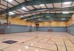 Interior del gimnasio del centro comunitario con cancha deportiva y techo industrial