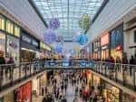 Interior del centro comercial con múltiples niveles, tiendas y decoración colgante