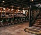 Interior del bar con barra larga y taburetes verdes
