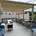Terraza exterior con mesas y sillas bajo pérgola de madera