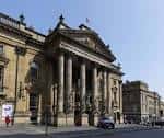 Fachada principal del Theatre Royal en Newcastle con columnas clásicas y cielo despejado