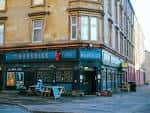 Vista exterior del pub The Maverick en Glasgow, mostrando su fachada en esquina con mesas al aire libre