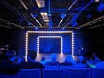 Escenario iluminado con luces LED y público sentado en evento nocturno