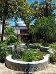 Jardín con fuente y palmeras frente al museo