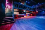 Interior del club con iluminación de colores y escalera