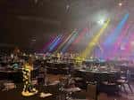 Interior del arena configurado para evento con mesas redondas, iluminación de escenario y ambiente festivo
