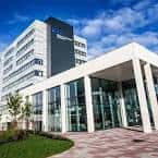 Vista exterior moderna del campus de Glasgow Caledonian University con fachada de cristal y cielo azul