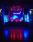Escenario interior del club con iluminación de neón azul y rojo