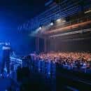 Interior del auditorio durante un evento con iluminación azul y público en las gradas