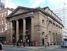 Vista exterior de la Portico Library en Manchester con fachada neoclásica y columnas