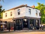 Fachada exterior de The Abbey pub en Manchester con terraza al aire libre