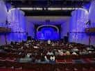 Interior del auditorio del Magik Theatre con iluminación azul y butacas rojas