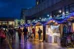 Vista nocturna del Cardiff Christmas Market con puestos iluminados y gente caminando