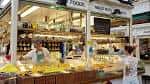 Interior del Cardiff Market mostrando un puesto de alimentos con productos frescos y clientes
