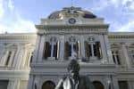 Vista frontal del edificio histórico de la UNLP con estatua en primer plano