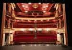 Interior del auditorio del New Theatre con butacas rojas, balcones y techo decorado
