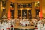 Salón de eventos del museo decorado para una recepción con mesas redondas y iluminación cálida